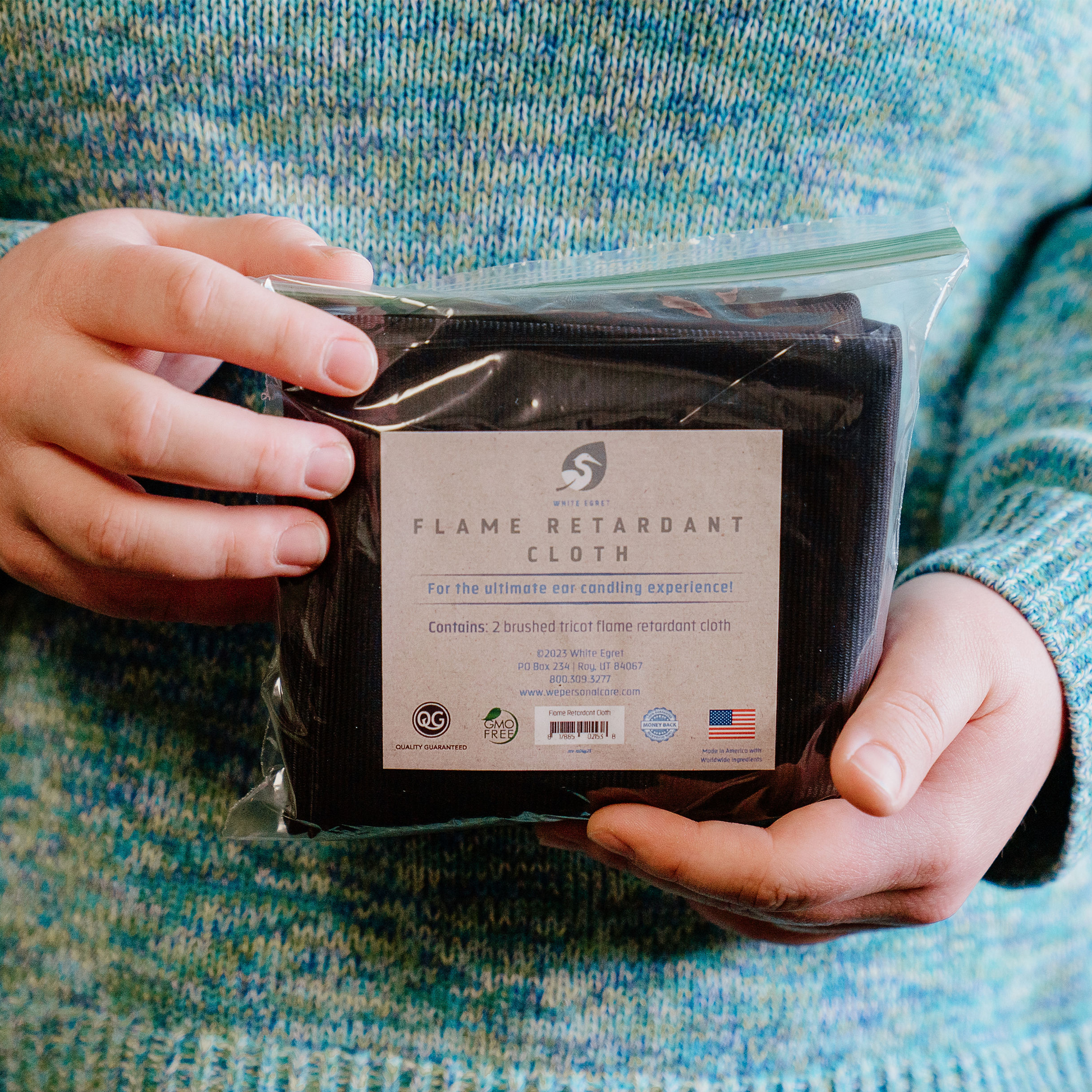 Person holding a bag of White Egret flame retardant cloth blue shirt