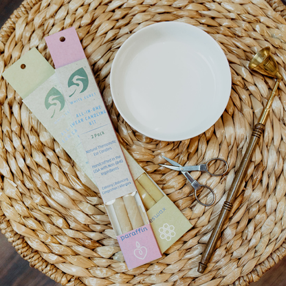 white egret ear candling products and accessories spread out on a wicker table with candle snuffer scissors and a bowl of water lifestyle image