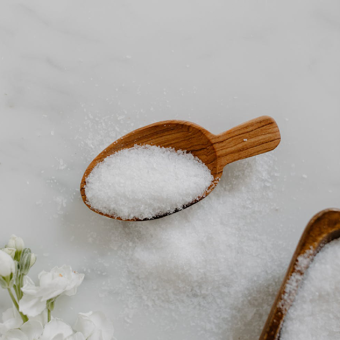 Closeup texture shot of epsom salt with wooden spoons and eucalyptus leaves